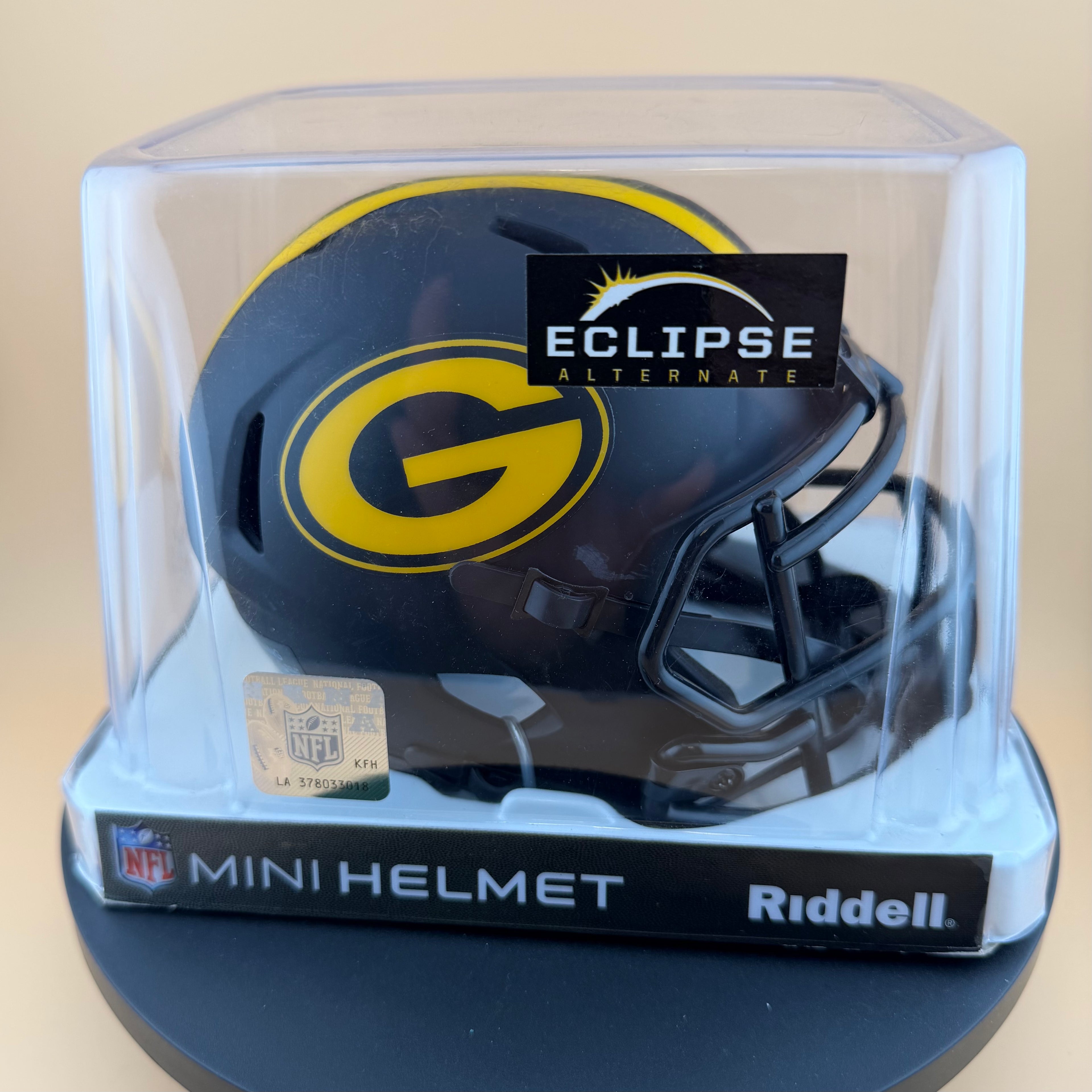 Mini football helmet in clear display case with 'Eclipse Alternate' label, on beige background