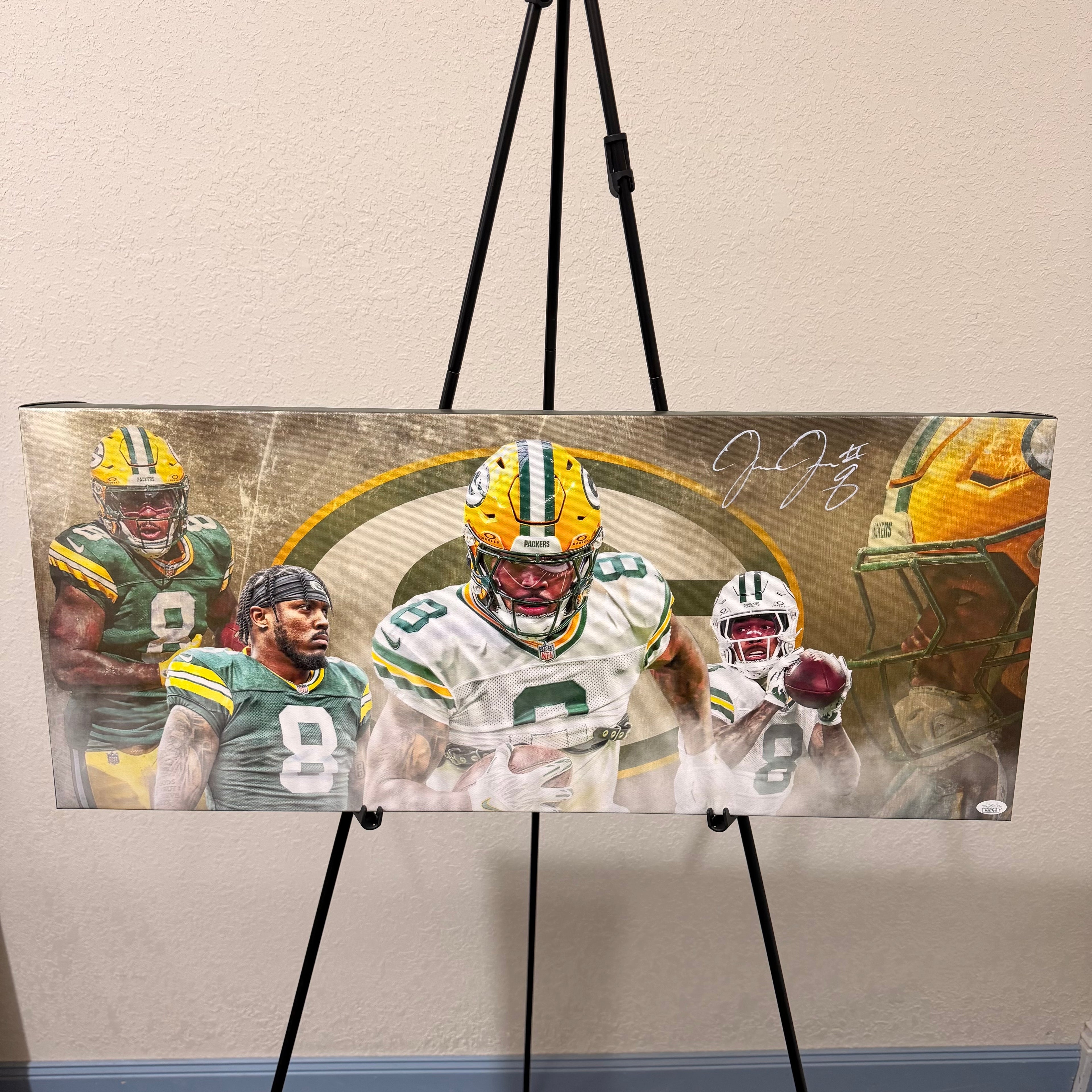 Autographed sports memorabilia featuring football players on a stand against a beige wall.
