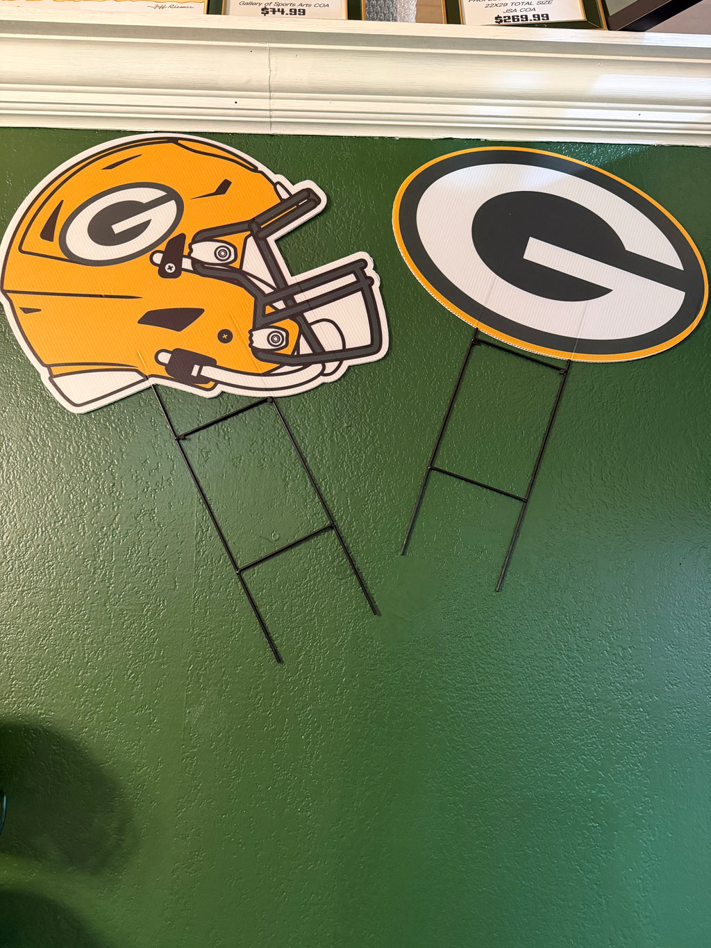 Green Bay Packers helmet and logo yard signs on a green surface.