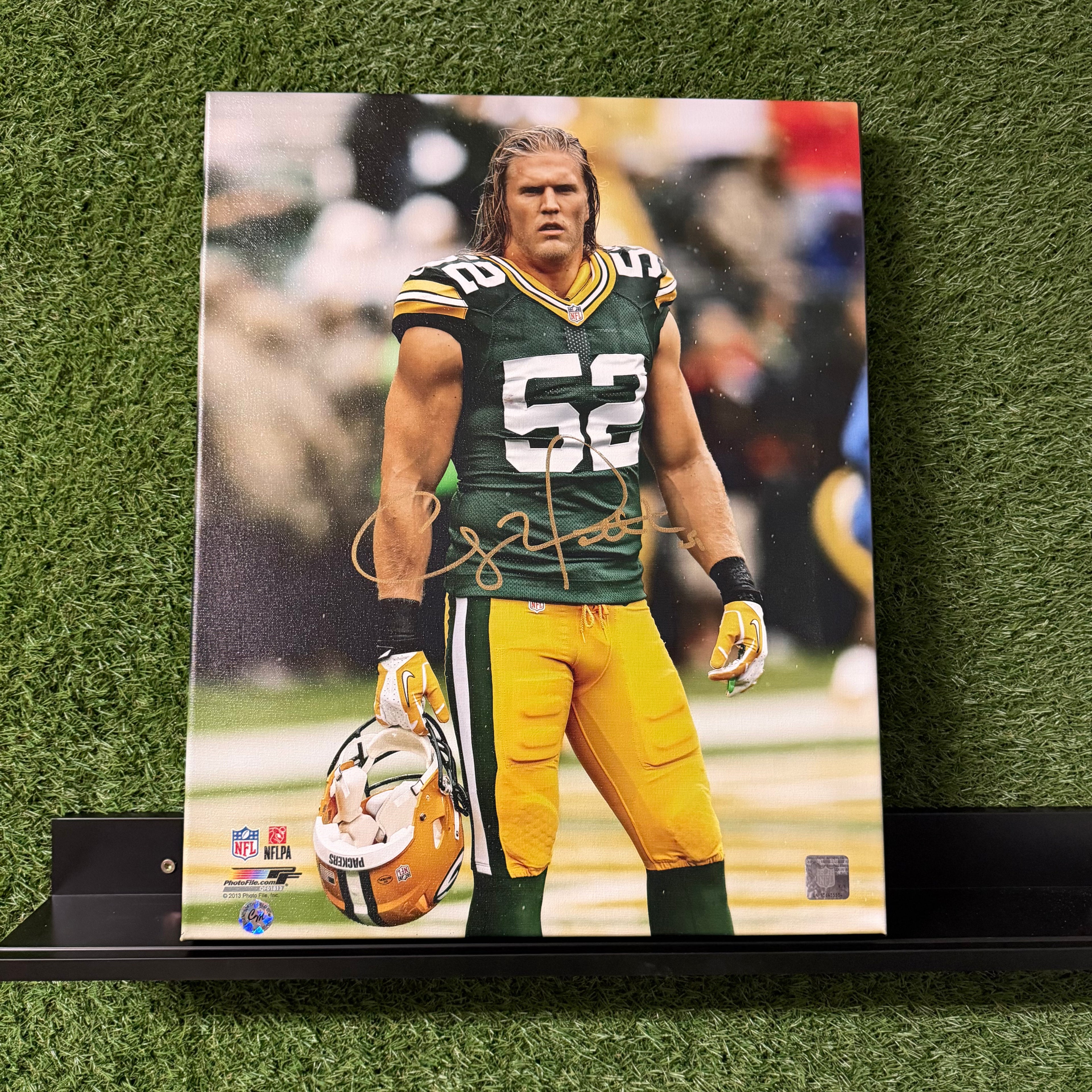 Autographed photo of a football player in green and yellow uniform on a grass background