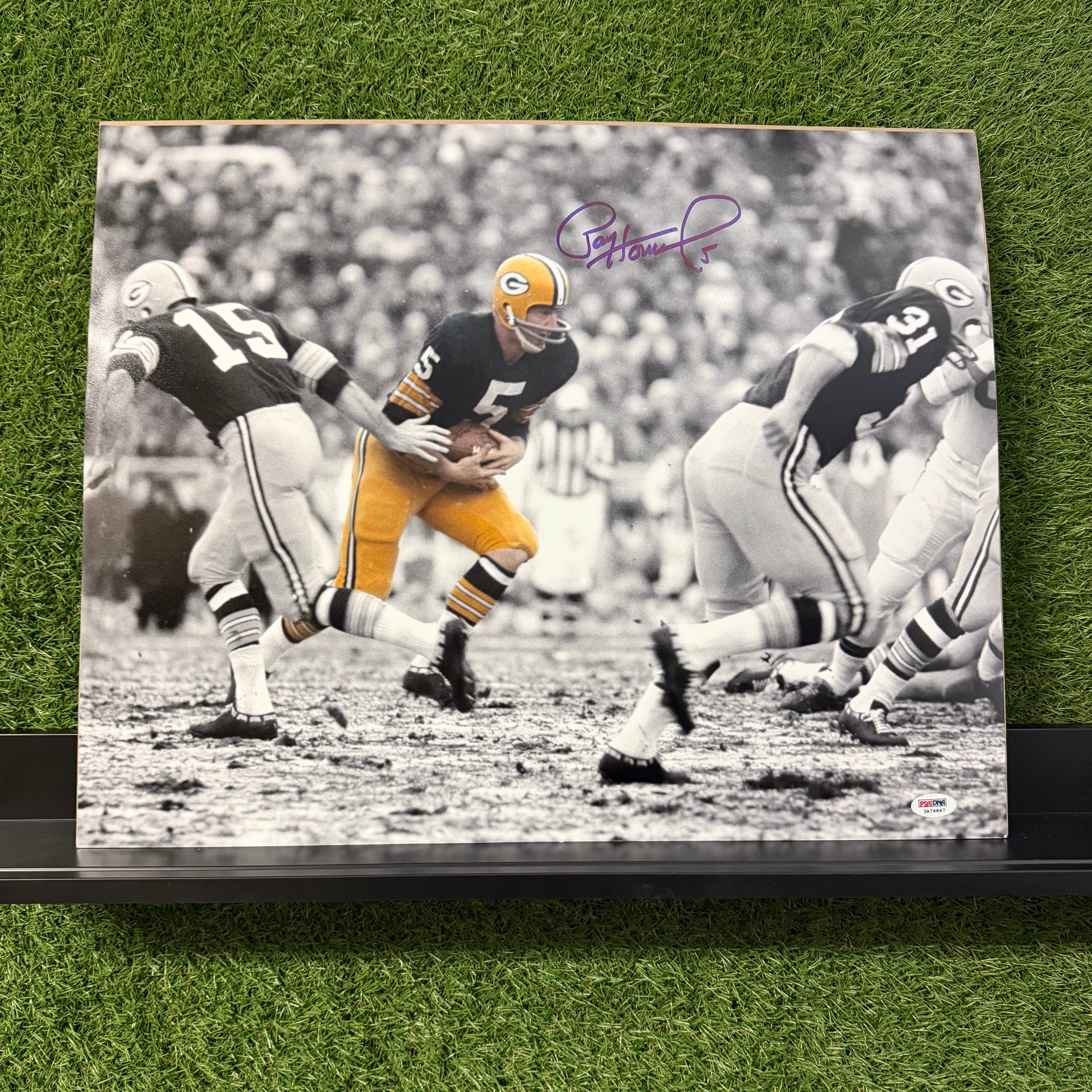 Framed black and white photo of a football player in action on grass